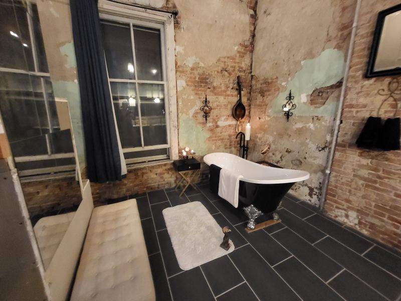 Original listing photo of the Champion House bath with clawfoot tub and exposed plaster